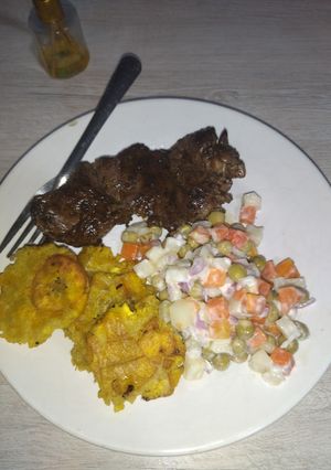 Una foto de Carne de res al vino tinto, acompañado de patacones y ensalada