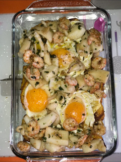 Una foto de Huevos estrellados con sepia y gambas