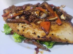 Una foto de Filete de pescado salteado con pimiento, sobre lecho de tomato y lechuga