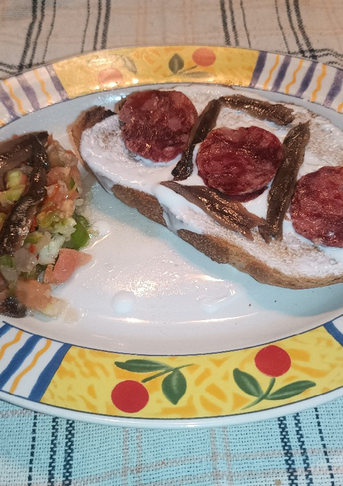 Una foto de Tostada de pan de pueblo con queso Kéfir, salchichón ibérico y anchoas