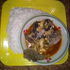 A picture of White rice and yellow stew with fresh fish.