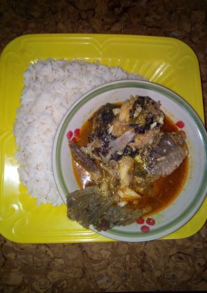 A picture of White rice and yellow stew with fresh fish.