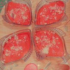 A picture of Jelly with strawberry chunks and almond topping.