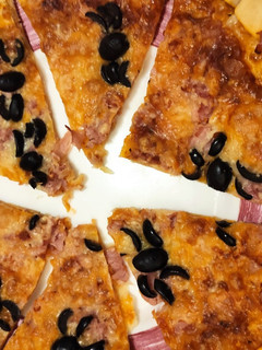 Una foto de Pizza de jamón dulce, queso y arañas (aceitunas negras)