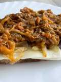 Tosta de berenjena mechada, cebolla caramelizada y queso
