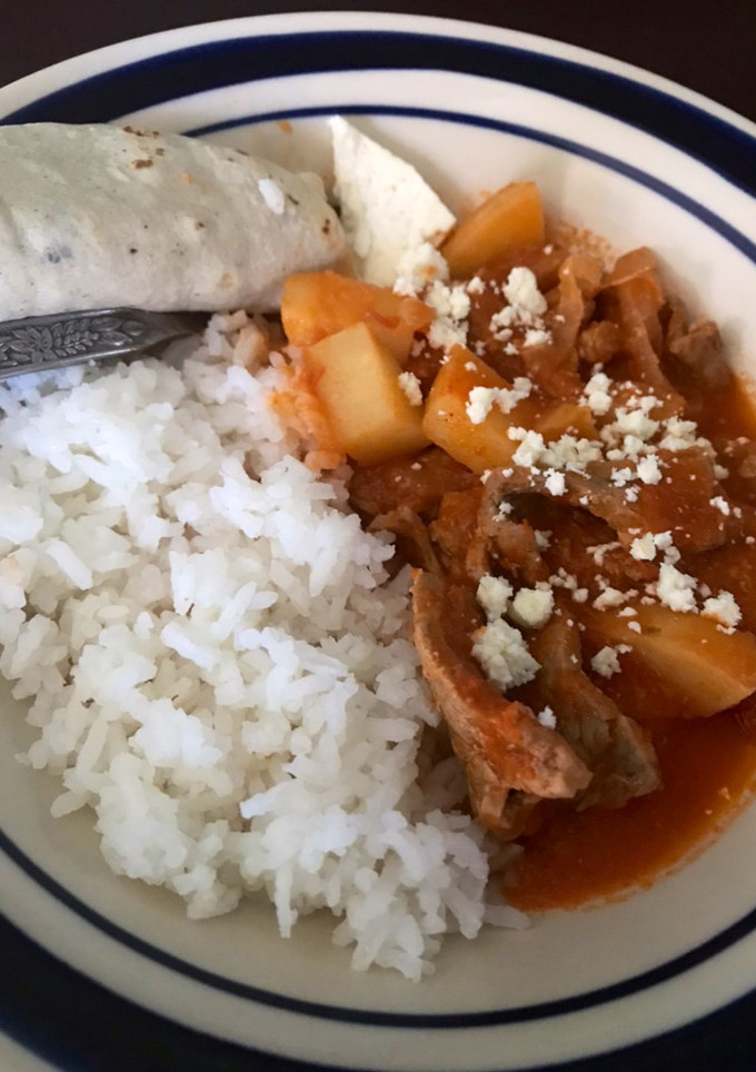 Una foto de Carne de res con salsa roja y papas