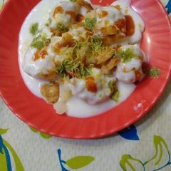 A picture of Dahi bhalla with green and red chutney.