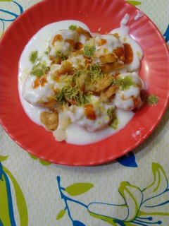 A picture of Dahi bhalla with green and red chutney.