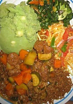 A picture of Mukimo served with beef stew and green vegetables.