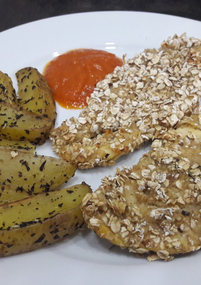 Una foto de Pollo con crujiente de avena y patatas gajo especiadas al horno