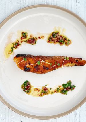 A picture of Grilled salmon served with homemade chimichurri sauce.