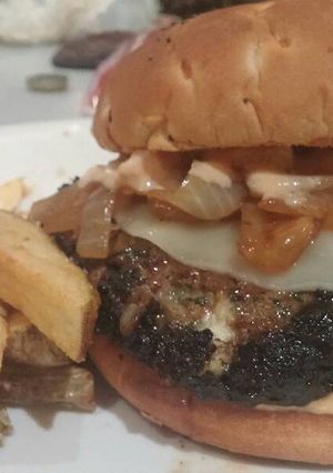 A picture of Beef, Lamb and Feta Burger with Provolone, Caramelized Onions and Russian Horseradish Dressing served with Garlic Fries.