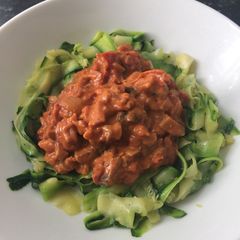 A picture of Bacon and mushroom sauce with courgette ribbons.