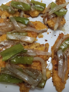 Una foto de Tiras de pollo empanado con sofrito de pimientos y cebolla