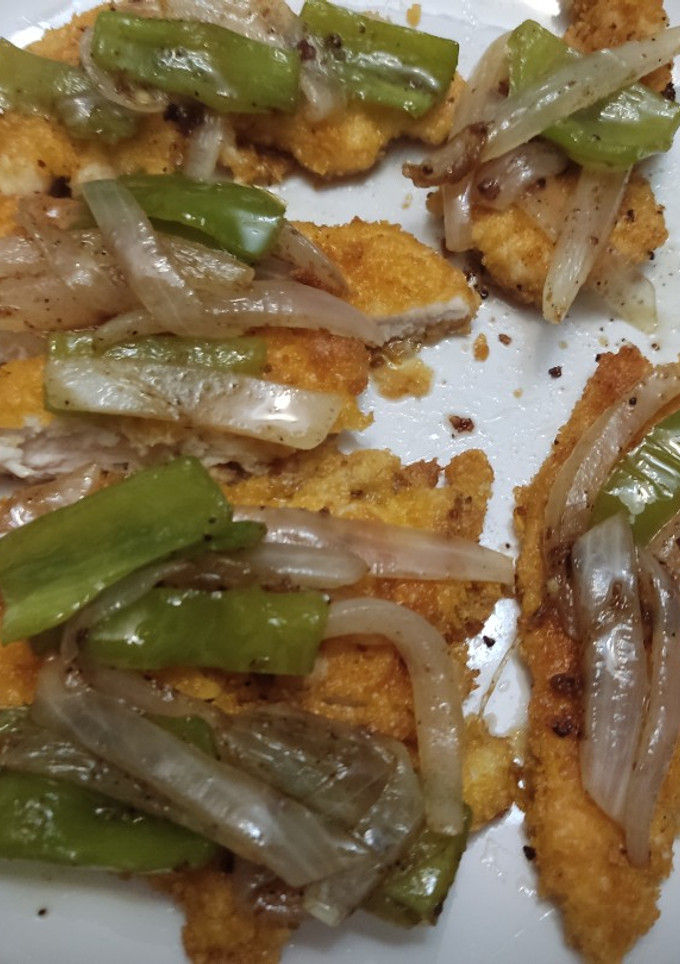 Una foto de Tiras de pollo empanado con sofrito de pimientos y cebolla