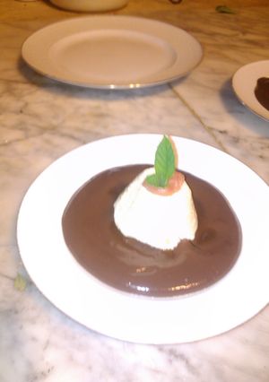 Una foto de Isla Flotante de vainilla sobre crema inglesa de chocolate