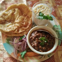 A picture of Panjabi chole bhature onion and Bundi ka Raita.
