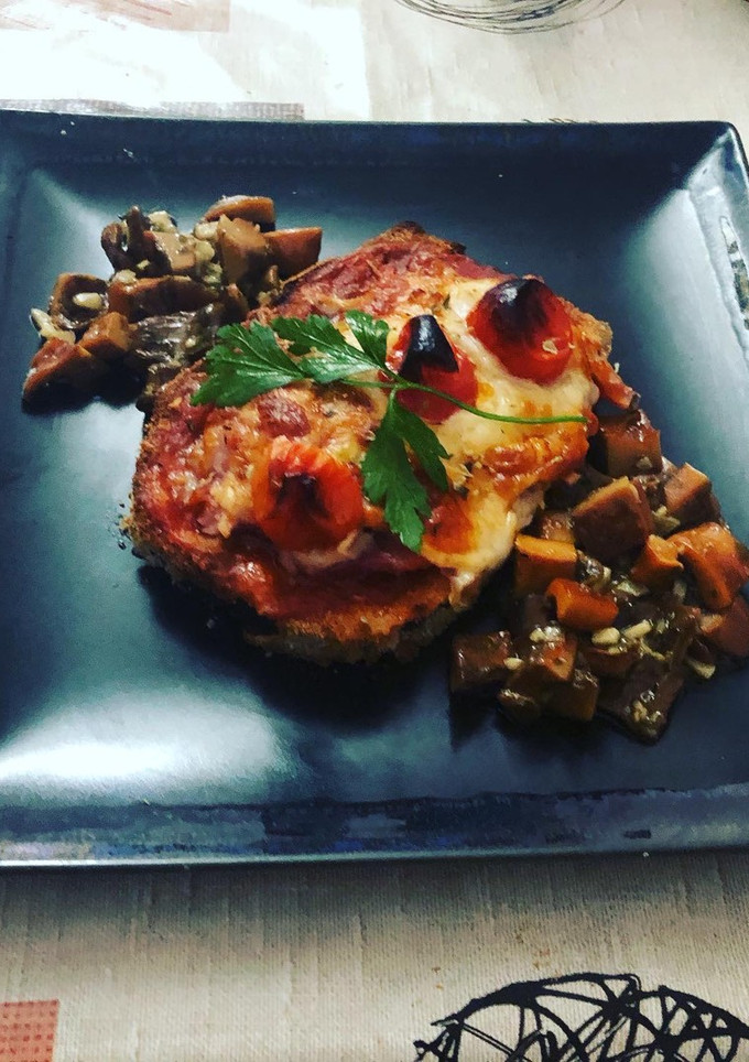 Una foto de Milanesa de berenjena a la napolitana con bolets al ajillo de guarnición