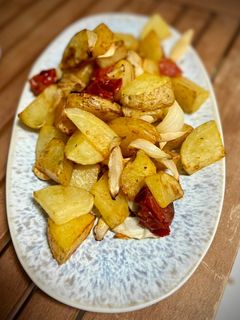 Una foto de Patatas en airfryer con tomates cherry y cebolla