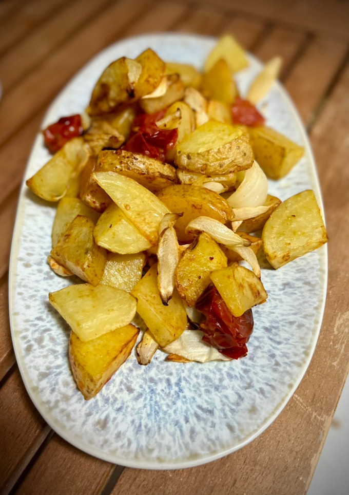 Una foto de Patatas en airfryer con tomates cherry y cebolla