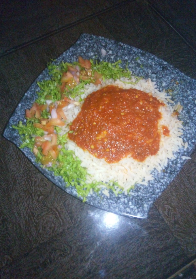 A picture of Rice and stew with lettuce salad.