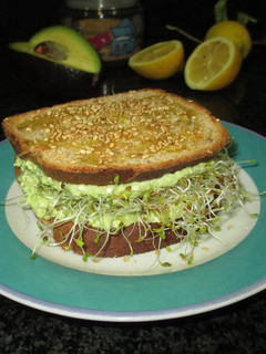 Una foto de Sándwich de pan integral con crema de aguacate, feta y brotes de alfalfa