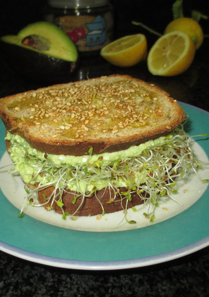 Una foto de Sándwich de pan integral con crema de aguacate, feta y brotes de alfalfa