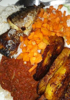 A picture of Rice with fried plantain,carrots and fried fish.