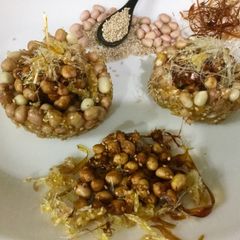 A picture of Caramalized peanuts in peanuts-sesame Katoris garnished with spun sugar.