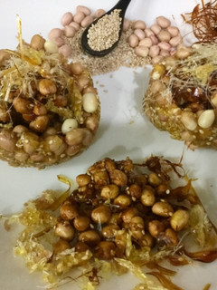 A picture of Caramalized peanuts in peanuts-sesame Katoris garnished with spun sugar.