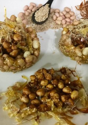 A picture of Caramalized peanuts in peanuts-sesame Katoris garnished with spun sugar.