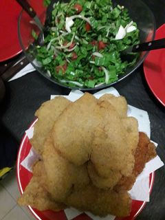 Una foto de Milanesas de pollo con ensalada de rúcula cherry y verdeo...