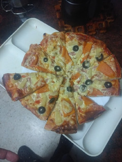 Una foto de Pizza hawaiana con papaya y piña