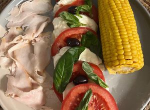Una foto de Ensalada de tomate con mozzarella con pavo y mazorca de maíz