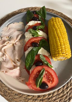 Una foto de Ensalada de tomate con mozzarella con pavo y mazorca de maíz