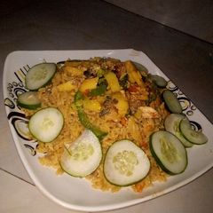 A picture of Jollof rice with fried Irish and fish sauce.