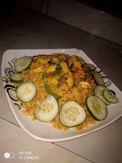 A picture of Jollof rice with fried Irish and fish sauce.