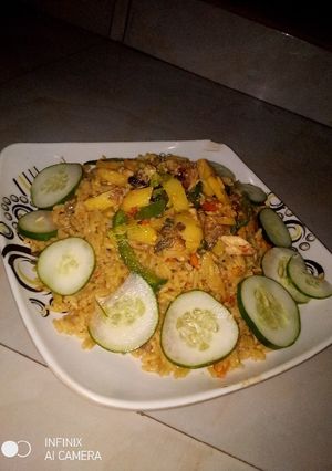A picture of Jollof rice with fried Irish and fish sauce.