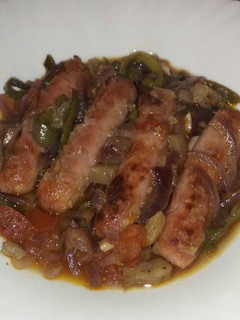 Una foto de Longanizas sobre verduras al horno