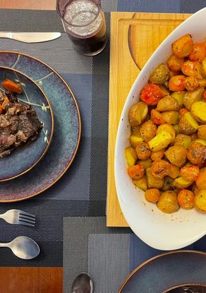 Una foto de Asado de tira en vino tinto con papas de colores al horno