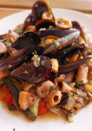 Una foto de Calamar troceado en salsa con mejillones y base de verduras a la brasa
