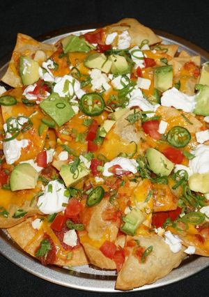 A picture of NACHOS WITH GOAT CHEESE, AVOCADO, AND SOUR CREAM.
