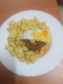 Una foto de Zócalo de pisto con huevo frito y papas fritas al ajillo