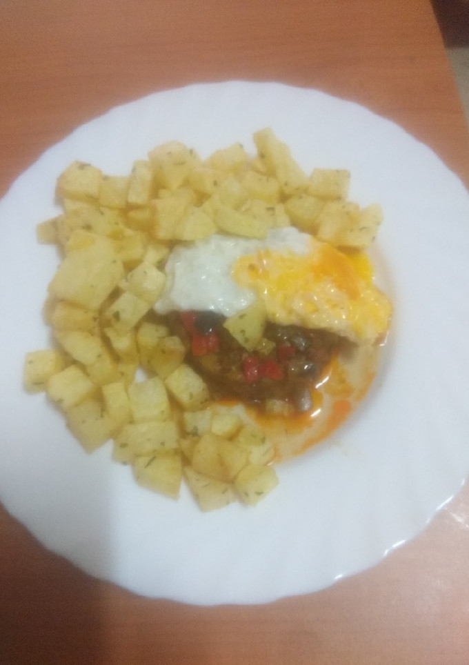 Una foto de Zócalo de pisto con huevo frito y papas fritas al ajillo