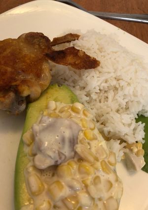 Una foto de Pollo frito con arroz y palta rellena de pollo y choclo dulce