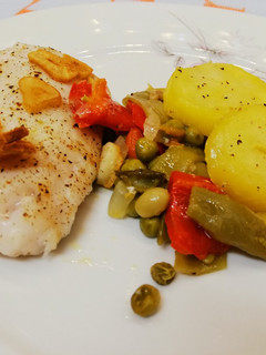 Una foto de Merluza horneada al ajillo con verduras y patatas