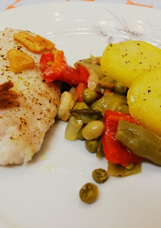 Una foto de Merluza horneada al ajillo con verduras y patatas