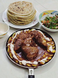 A picture of Chicken Gravy and Potato Paratha with Raita and Salad.