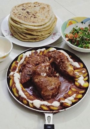 A picture of Chicken Gravy and Potato Paratha with Raita and Salad.