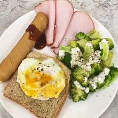 A picture of Egg on toast with sausage, ham and broccoli salad.